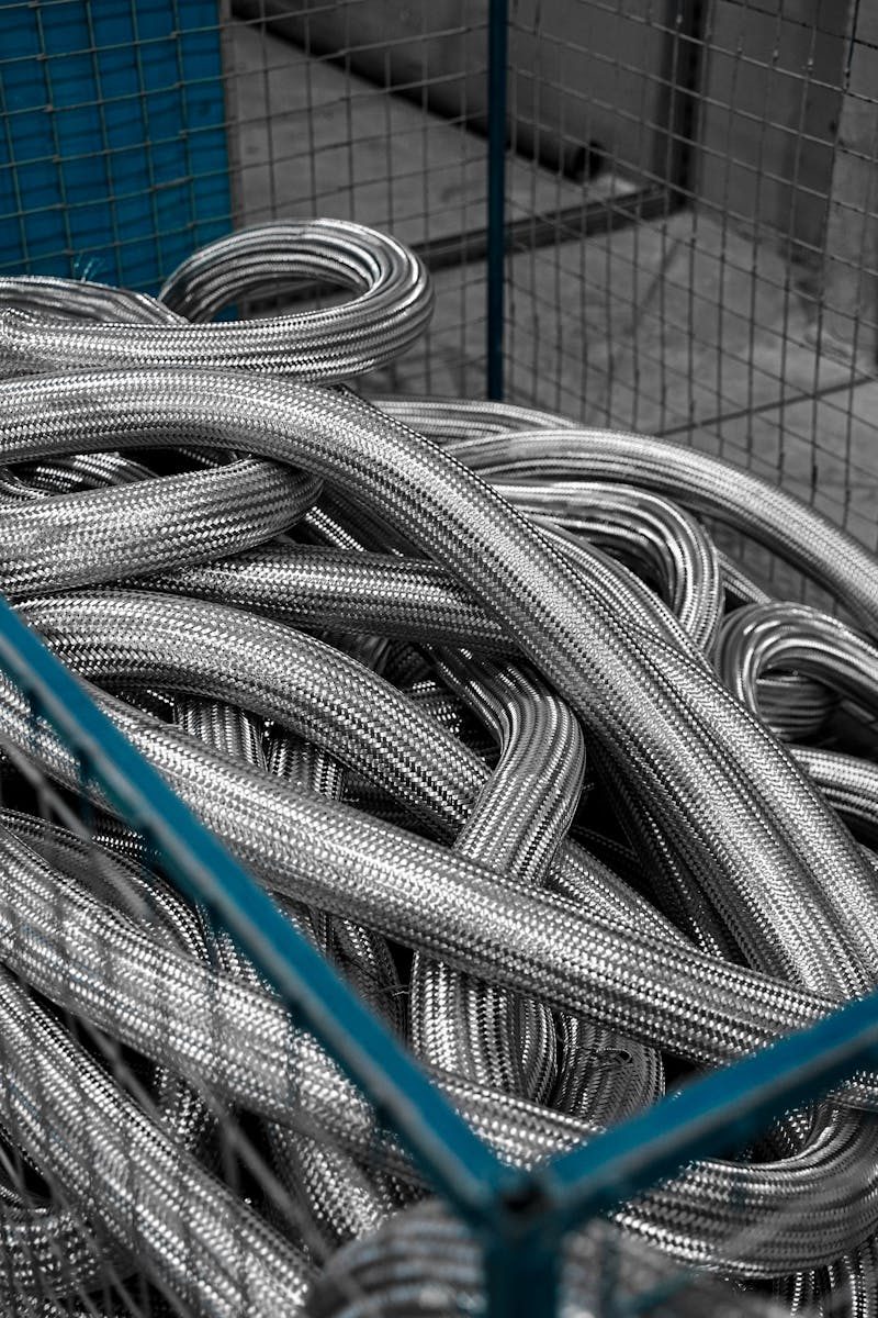 Close-up view of coiled metallic tubes inside an industrial cage, showcasing engineering materials.