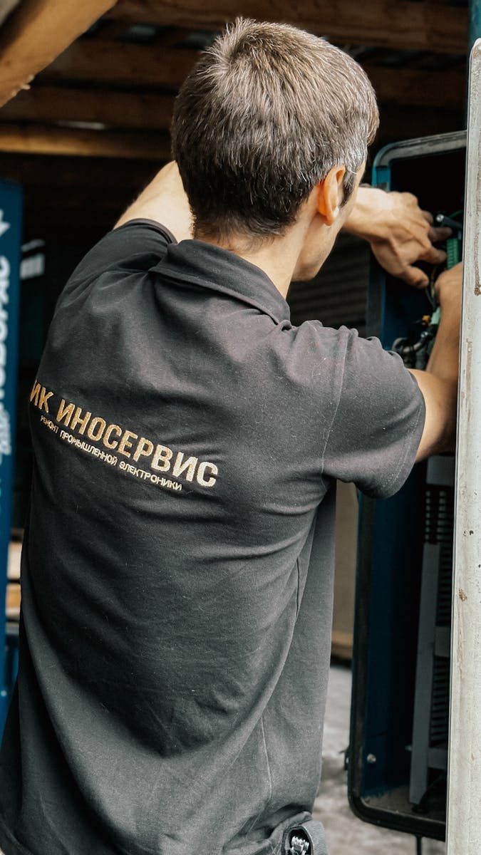 Male technician fixing machinery in an industrial setting, showcasing professional maintenance work.